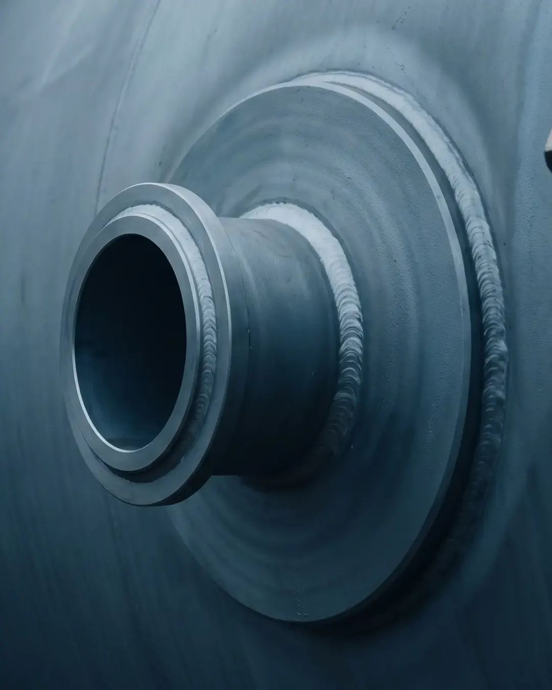 Macro of a nozzle-to-shell junction on a pressure vessel in cold tone