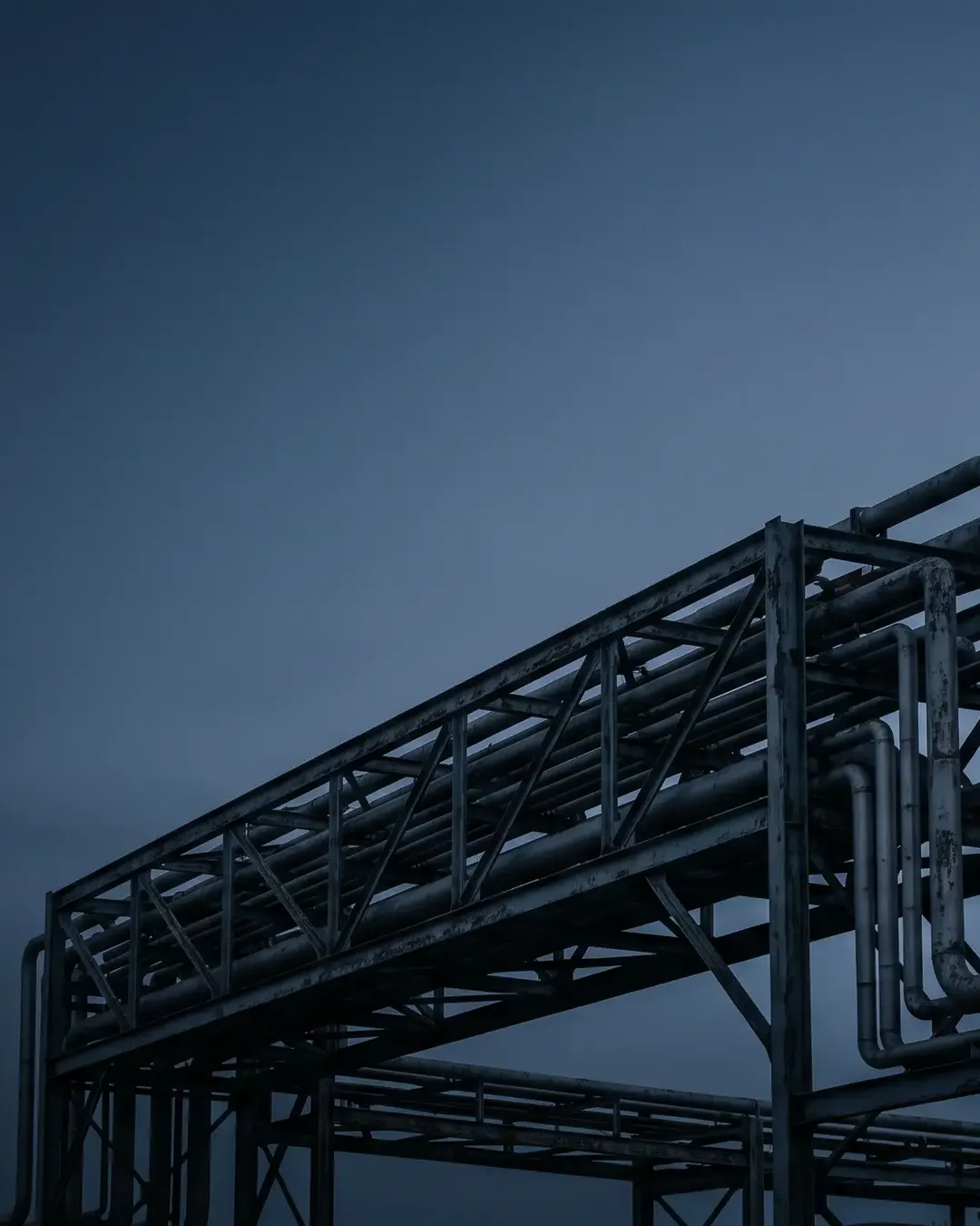 A weathered, ageing pipe rack silhouetted at dusk