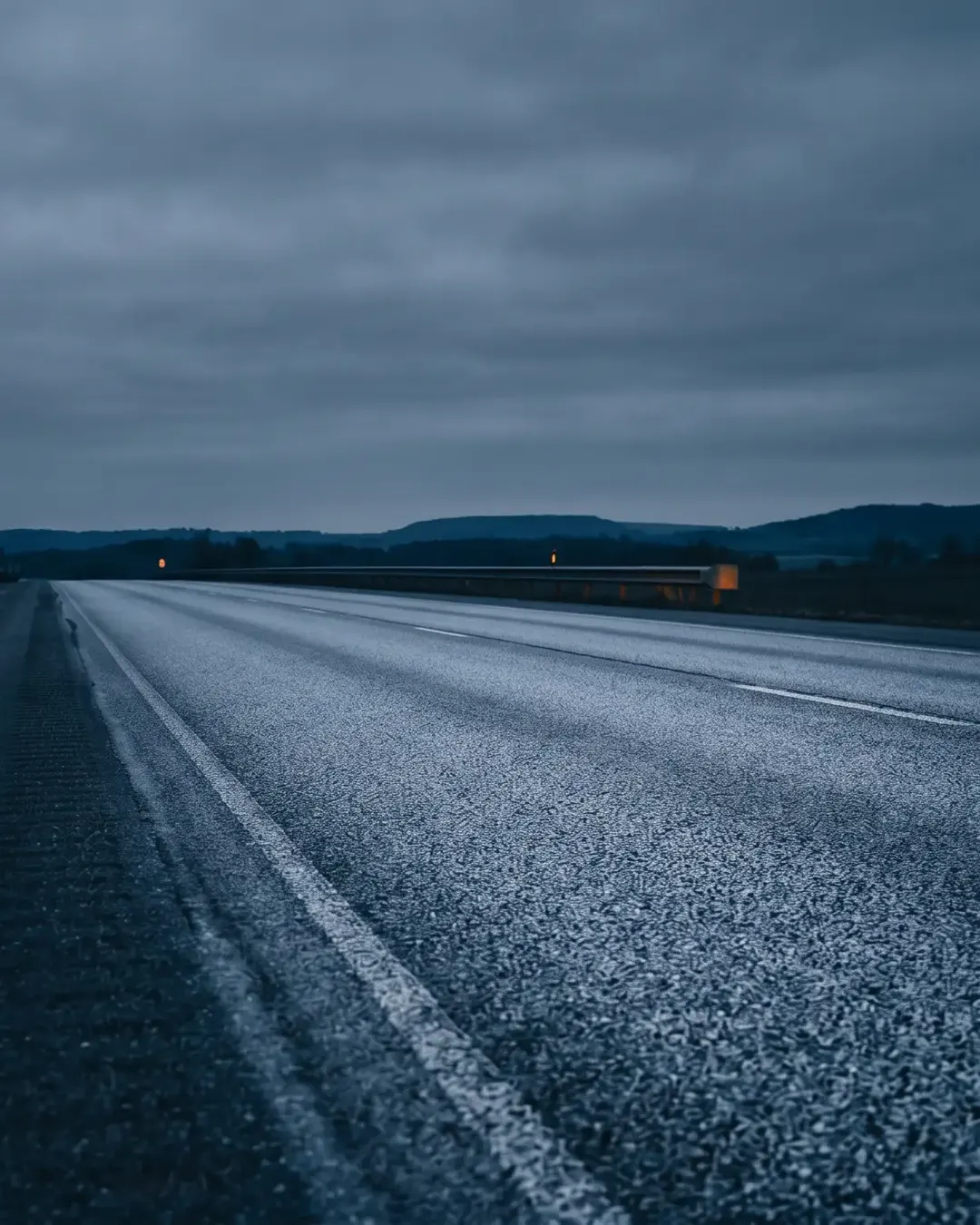 A road surface receding toward a low horizon at dusk in cold tone
