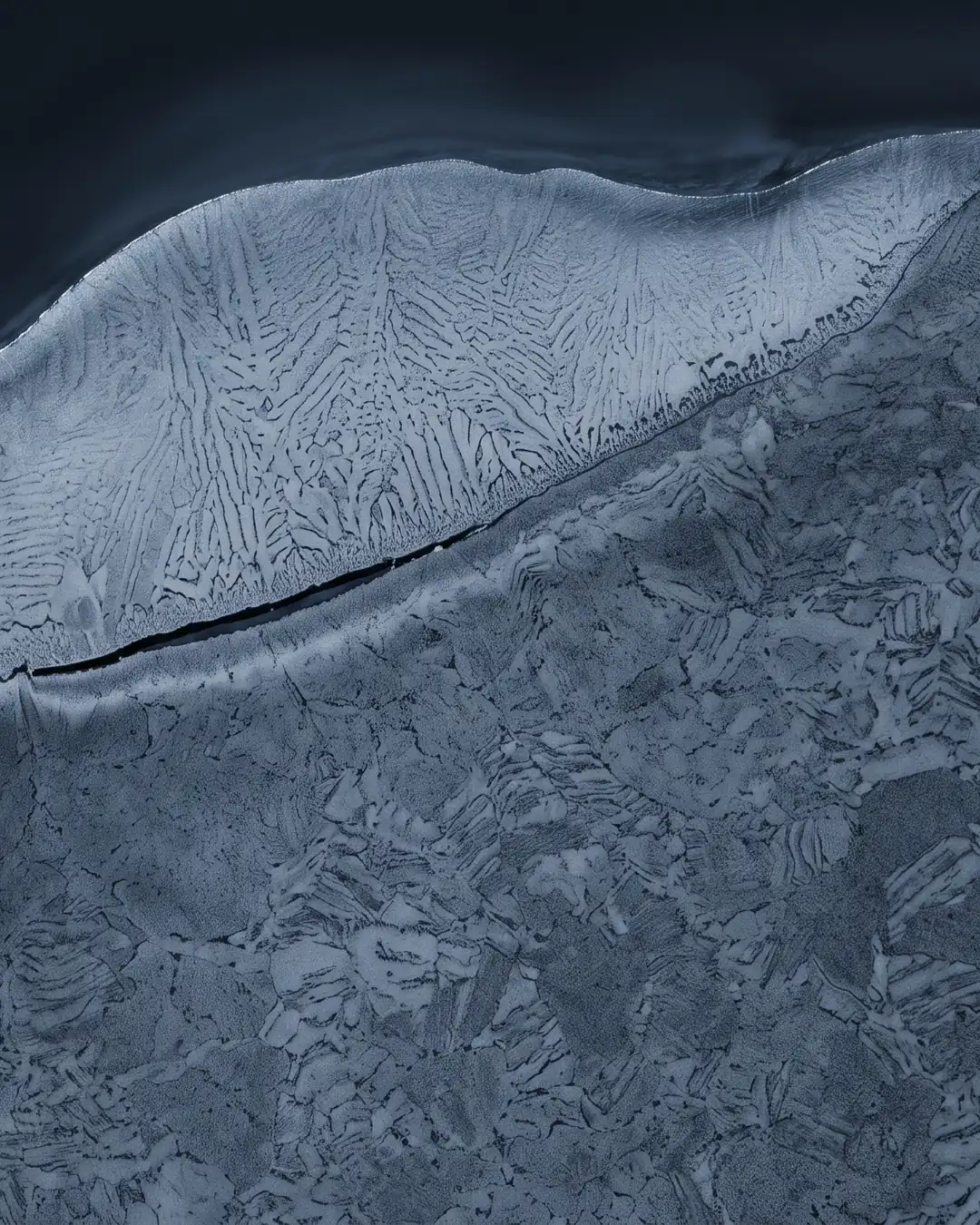 Macro cross-section of a stainless weld overlay on a thick steel plate, with a hairline separation opening along the fusion line
