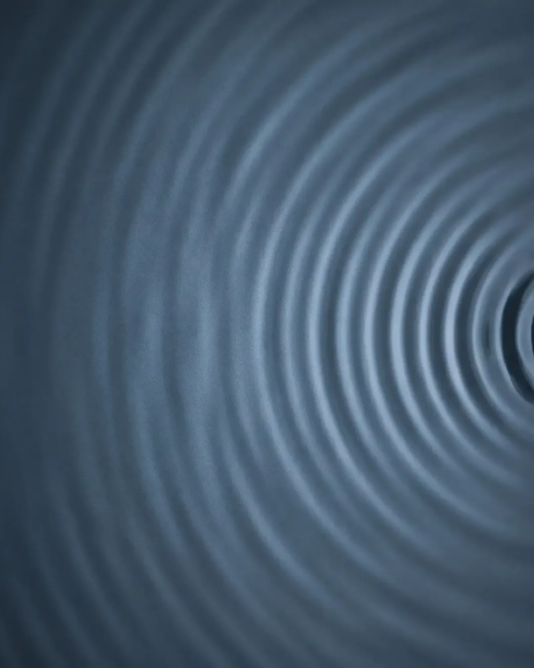 Abstract visualisation of an ultrasonic wavefront, concentric arcs of pale steel-blue light propagating through a dark medium