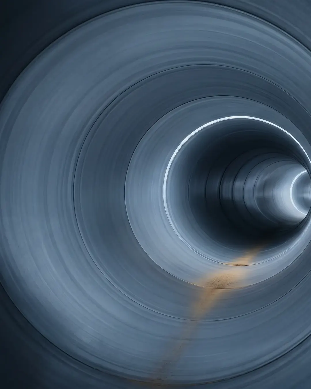 The interior bore of a large pipe receding to a faint light ring