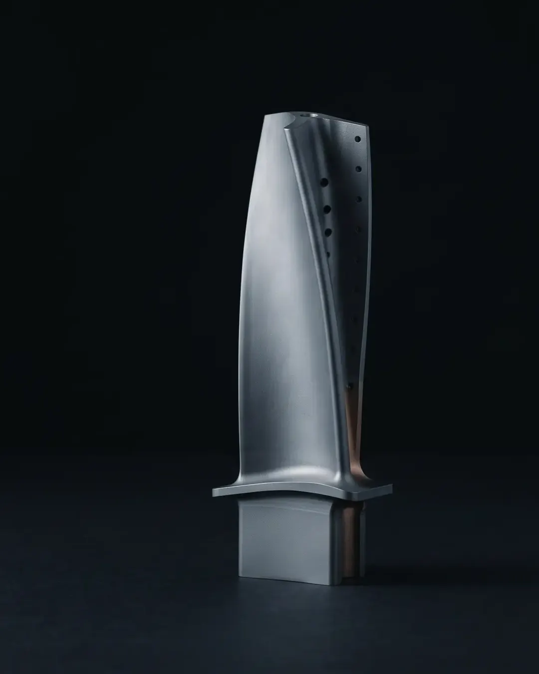 A single-crystal turbine blade rendered as pure form against a black seamless ground
