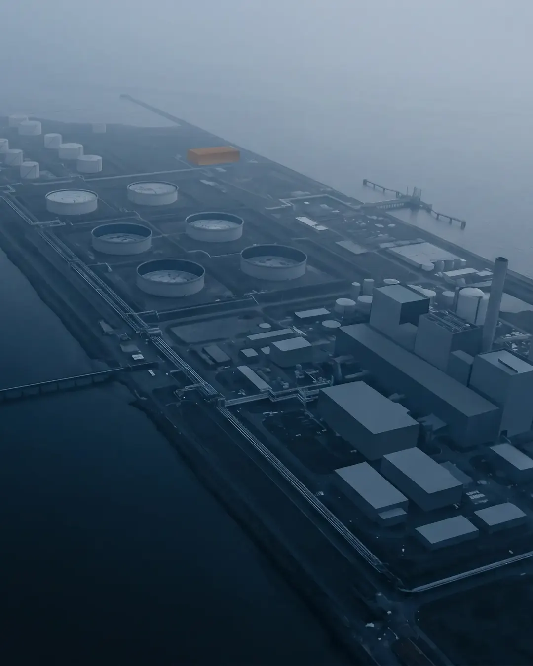 Aerial view of a mixed industrial coastline at dawn, reduced to abstract grey-blue shapes