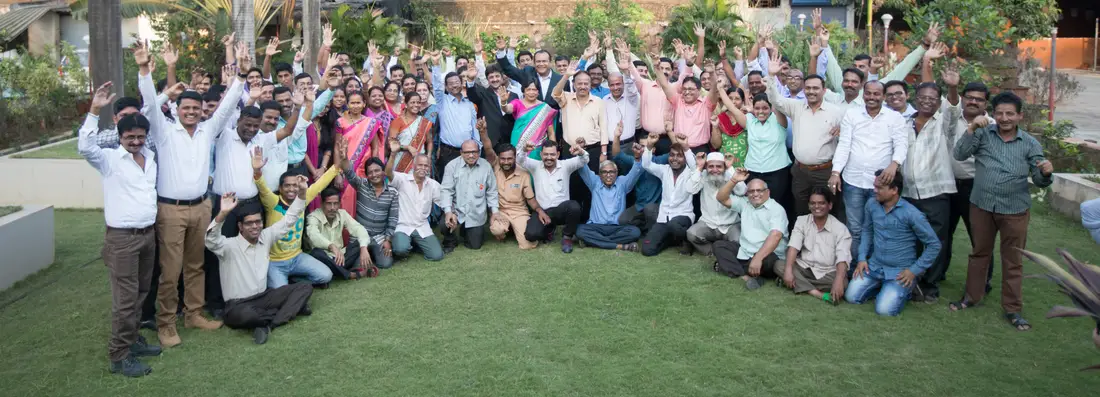 TCR Engineering staff with arms raised at a company gathering on the lawn at Mahape
