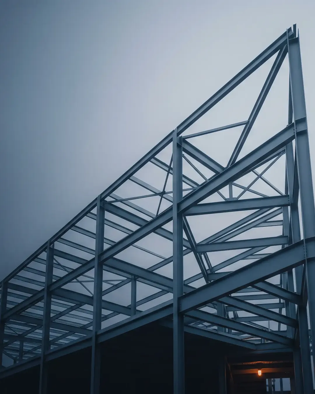 A rising steel structure sweeping upward against a graded dawn sky