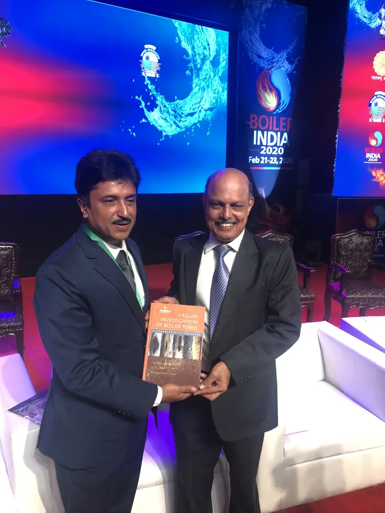 Paresh Haribhakti presenting a copy of Failure Investigation of Boiler Tubes to a delegate on stage