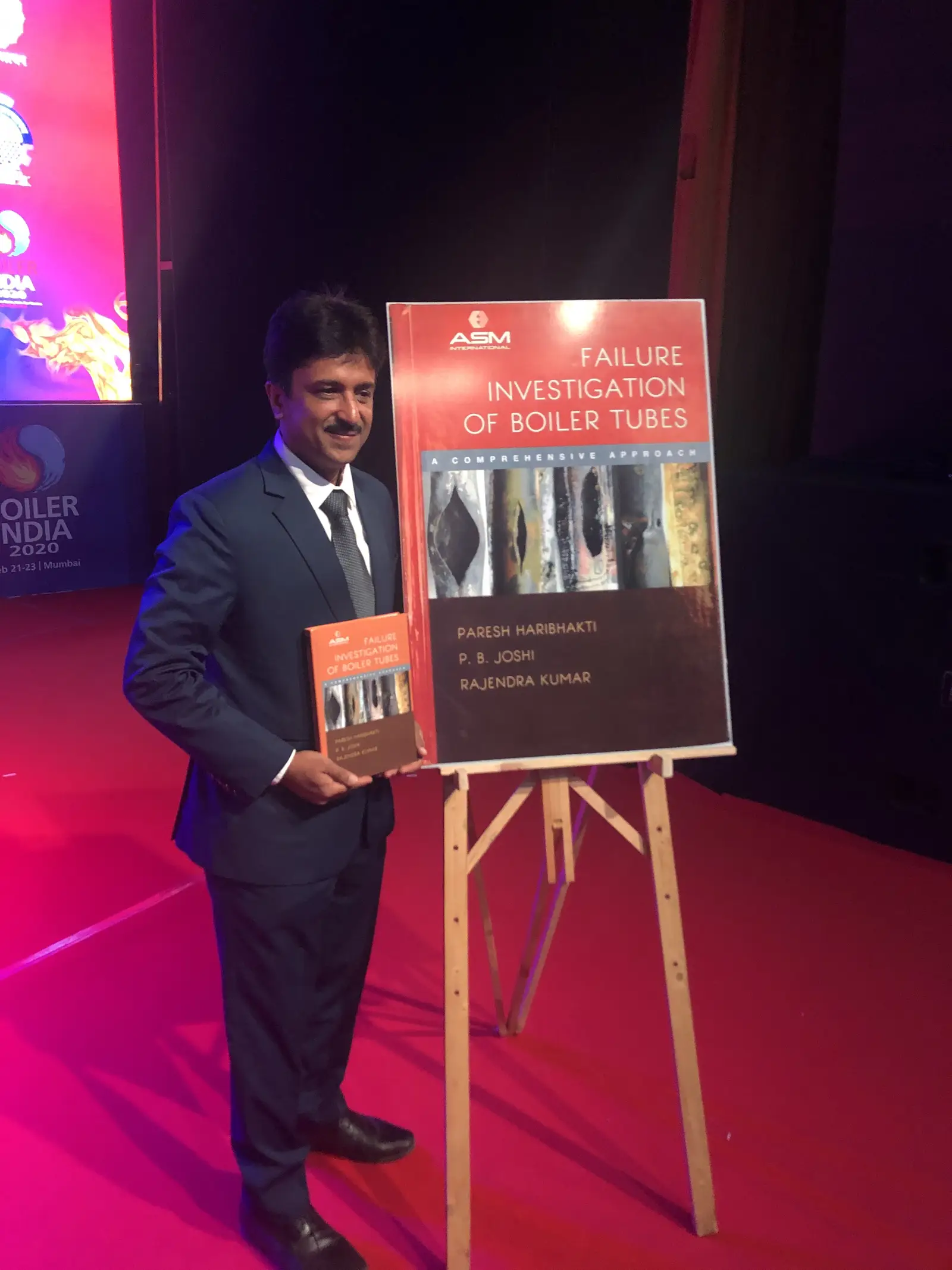 Paresh Haribhakti beside the poster of the book cover, Failure Investigation of Boiler Tubes, ASM International, by Paresh Haribhakti, P. B. Joshi and Rajendra Kumar