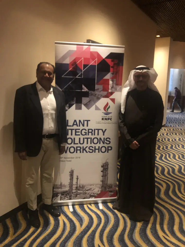 Paresh Haribhakti with a KNPC host beside the Plant Integrity Solutions Workshop banner
