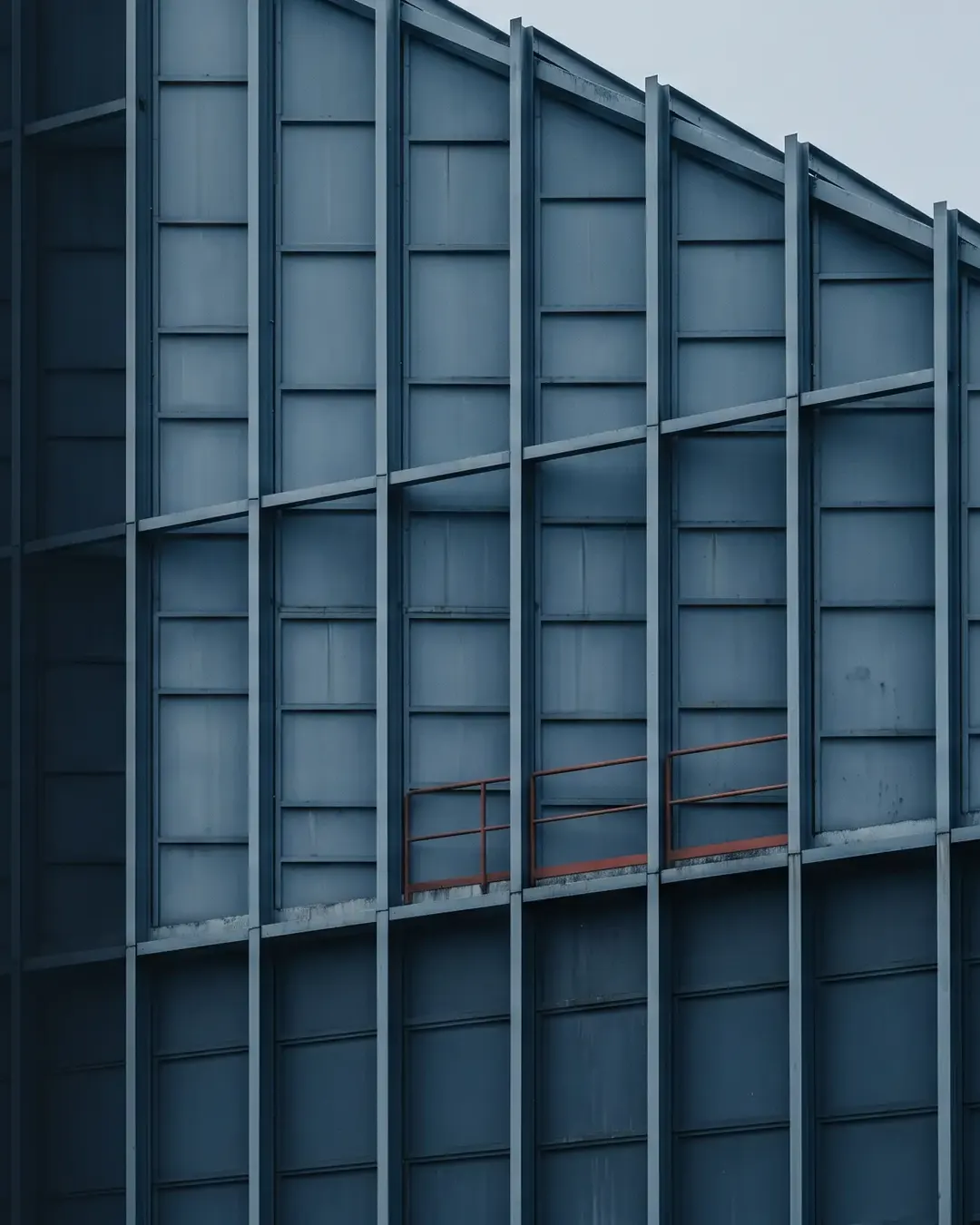A cold industrial facade reduced to a regular grid of light and shadow